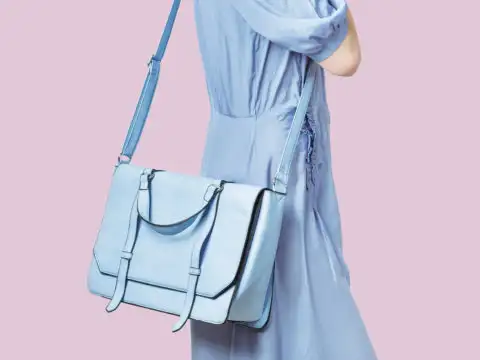 Woman in blue dress holding blue purse on a pink background