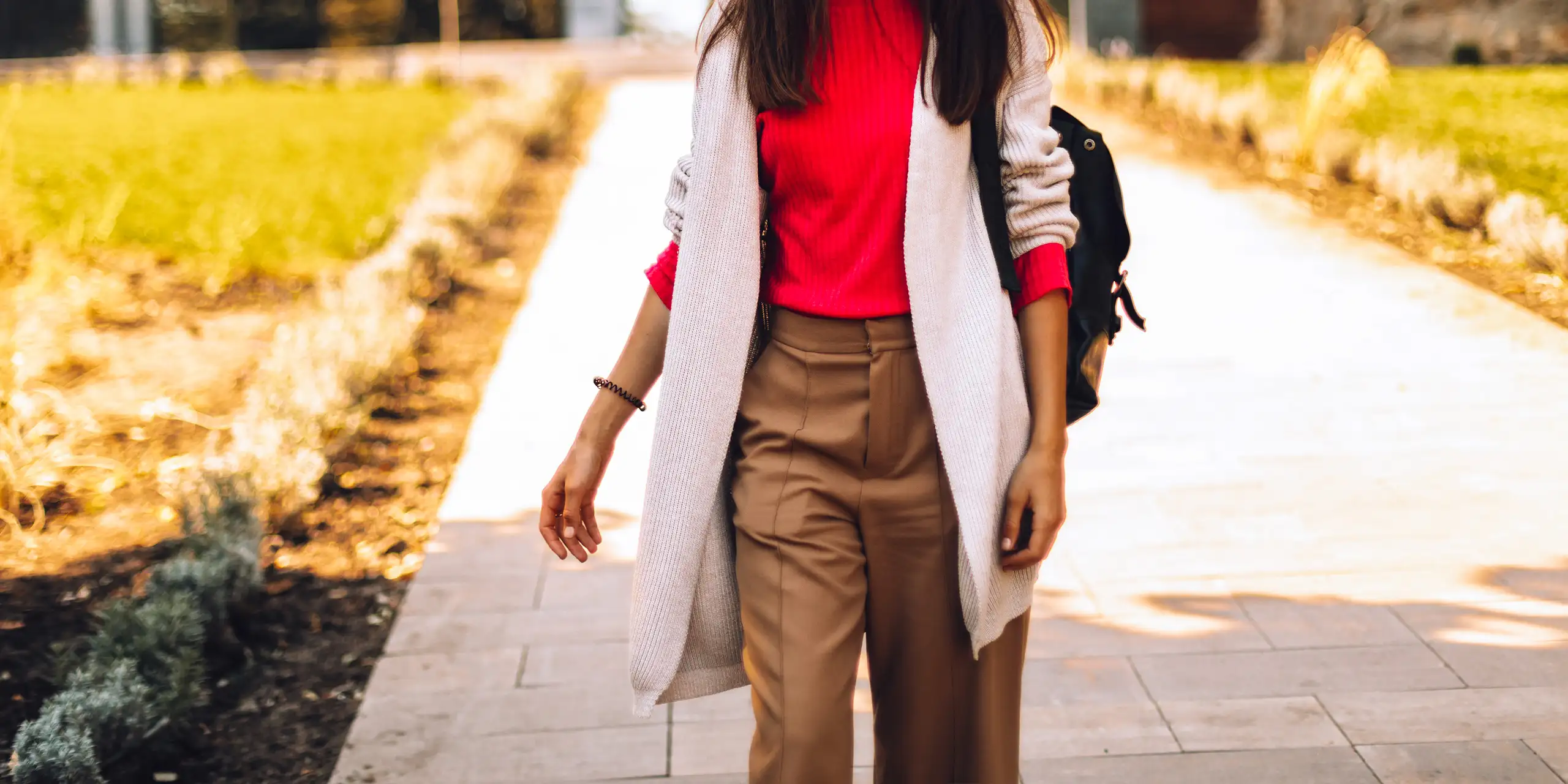 woman walking in park wearing travel pant and backpack; Courtesy of Ekateryna Zubal/Shutterstock